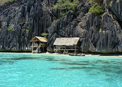 huts on Banol Beach with karst cliffs in the background