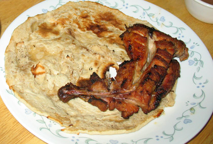 a piece of chicken tikka and naan bread on a plate